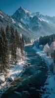 Serene winter landscape with a flowing river and majestic mountains in the background during a clear daytime in a forested area photo