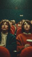Two young adults watch a film in a crowded theater, captivated by the screen's glow during an evening outing photo