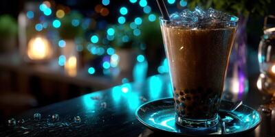 Frosty bubble tea served in a transparent glass on a table illuminated by colorful lights at a nighttime cafe photo