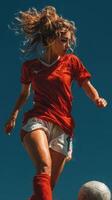 Young athlete performs skillful soccer move under bright blue sky during afternoon play photo