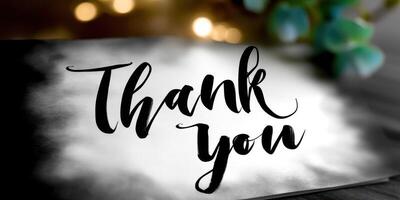 Handwritten thank you note on blurred background with decorative elements and warm lighting ambiance photo