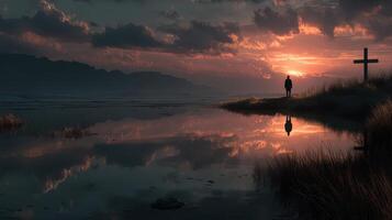 Stunning sunset reflection over a calm lake with a silhouette of a person standing near a cross photo