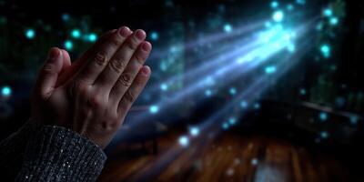 Hands together in prayer with soft light effects illuminating a serene space at night photo