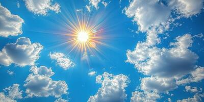 Bright sun shining through fluffy clouds in a clear blue sky during midday photo