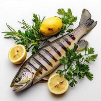 A fish with lemon slices and herbs on a white surface photo