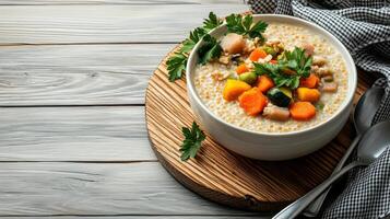 A bowl of oatmeal with vegetables and herbs on a wooden table photo
