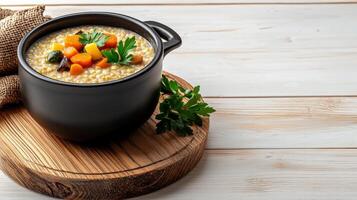 A bowl of soup with carrots and parsley on a wooden board photo