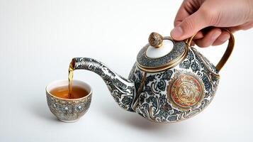 A person pours tea into a cup from a teapot photo