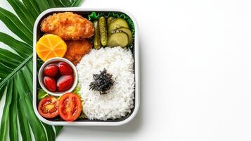 A bento box with rice, vegetables and a tomato photo