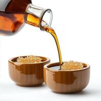 Syrup pouring into two small bowls with sugar photo