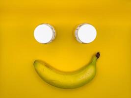 Smiley face made of one banana and two medicine bottles in the center of the image, top view photo