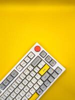White keyboard on yellow background with bright red and yellow keys. Flat lay. Top view, copy space. ad. Vertical photo. photo