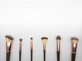 Several makeup brushes lined up on a white background, copy space, flat lay, top view photo
