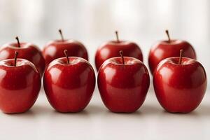Glossy red apples placed symmetrically on a clean white surface with soft natural lighting. photo