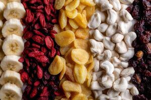 Dried fruits, nuts, and banana chips arranged in colorful vertical stripes for a healthy snacking experience photo