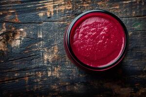 Beetroot hummus in glass jar on rustic wooden table photo