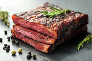 Slices of smoked beef brisket with rosemary and peppercorns on dark background photo