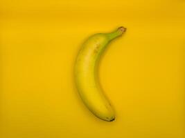 Bright yellow banana on yellow background in the center of the image, top view photo