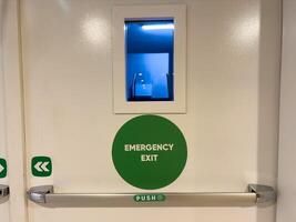 Green emergency fire exit sign or fire escape on ceiling for doorway or door exit in the building for evacuation in the event of a fire and safety prevent or prevention and rescue. photo