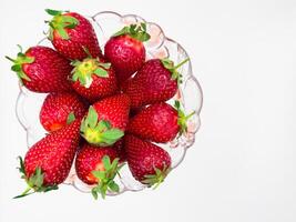 Fresh strawberries in a bowl against a white background, copy space, flat lay, top view photo
