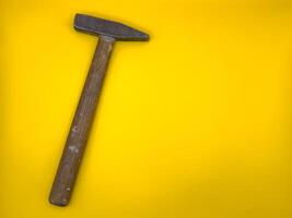 Rusty old hammer with wooden handle on yellow background. Flat lay. Top view, copy space. photo