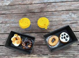 Two servings of donuts and a glass of tea on a wooden table photo