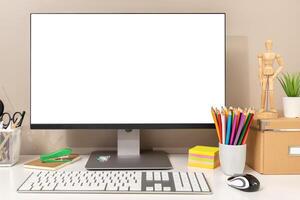 Workspace showing computer with white blank screen, keyboard, mouse and various stationery items, ideal for designers, students or creative workers. Template mockup photo