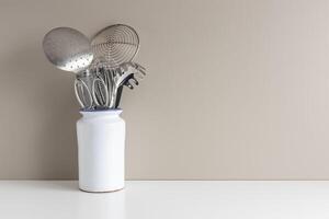 kitchen utensils in vase on table with copy space for menus and recipes. Minimalist cooking background photo