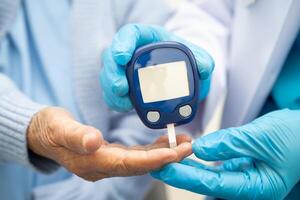 doctor using digital glucose meter for check sample blood sugar level to treatment diabetes. photo