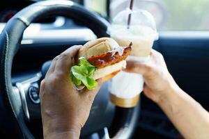 Asian woman driver hold and eat hamburger food photo