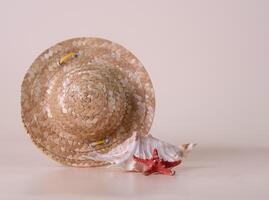 straw hat, shell, starfish on beige background, vacation mood, copy space, selective focus photo