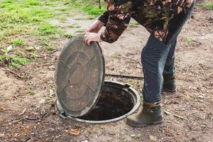 A man opened the septic tank hatch to check the sewer drain level. Septic tanks in a country house. photo