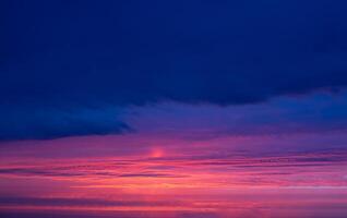 Panorama of a beautiful bright dark blue with crimson sunset in the evening sky. photo