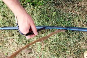 A man installs a drip irrigation system in a garden by melting a HDPE pipe with a hole punch to install adjustable water drippers photo