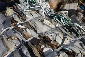 Discarded paper and plastic waste bundled together for efficient processing at a recycling center during bright daylight hours photo