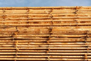Piles of wooden beams rest against a blue sky, showcasing their natural color and texture in a construction area photo