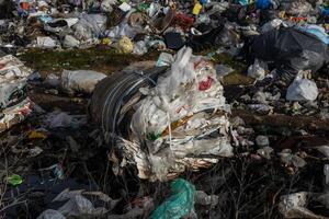 A large pile of waste materials dominates the landscape, highlighting serious issues of pollution and waste management in urban environments photo