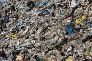 A vast pile of mixed waste is visible, showcasing discarded textiles, plastics, and debris. This landfill reflects ongoing environmental challenges photo