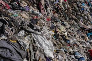 A sprawling landfill showcases a mixture of brightly colored fabrics and plastics piling up, highlighting ongoing pollution issues in the ecosystem photo