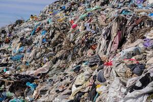 A vast landfill stacked with clothes, plastic, and trash underscores urgent pollution issues and the need for recycling photo