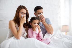 Family suffering from a cold or flu symptoms in bed using tissues with expressions of sadness and discomfort at home photo