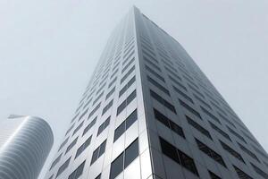 Low angle perspective of a modern skyscraper against a foggy sky representing urban architecture and development photo