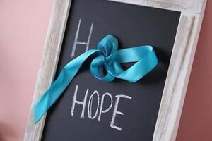 Inspirational close up photograph of a chalkboard with the word hope and a teal ribbon bow suggesting positivity and encouragement. photo