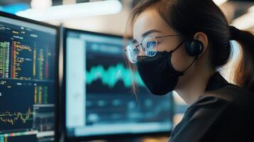 Focused individual wearing mask at computer monitor. photo