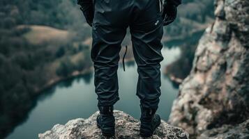 Person standing on a rocky outcrop overlooking a valley. photo