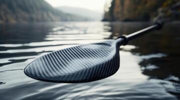 Close-up view of a carbon fiber kayak paddle in water. photo