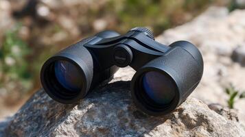 Close-up view of a modern black binoculars resting on a rock. photo