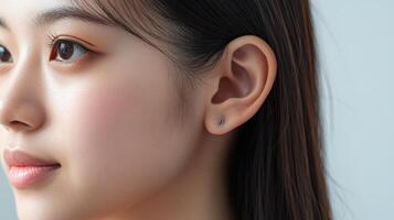 Close-up profile view of a woman's face and earlobe with small studs. photo