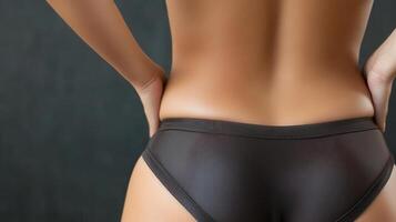 Close-up view of a woman's lower back and backside in dark brown undergarments. photo