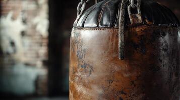 Aged leather punching bag hanging in a dark gym. photo